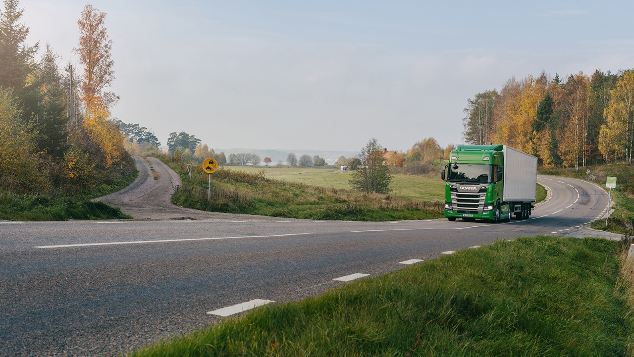 Grøn Scania lastbil kører alene på vejen