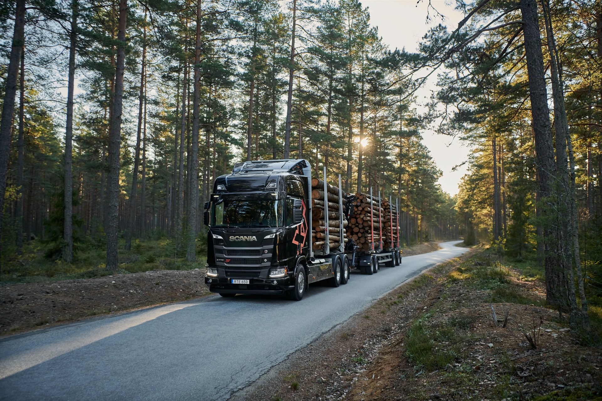 En Scania XT-lastbil för skogstransportsom kör timmer på en skogsväg