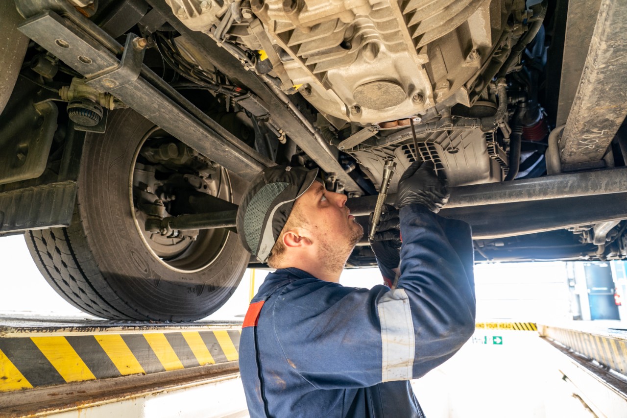 Technician working under a truck in workshop